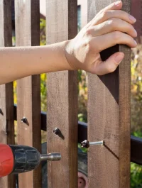 Close up of hand screwing wood plank to metal construction.