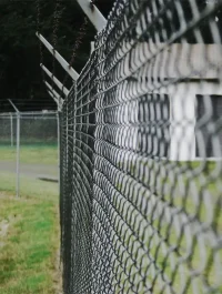 Close up on an aluminum chain link fence at night.
